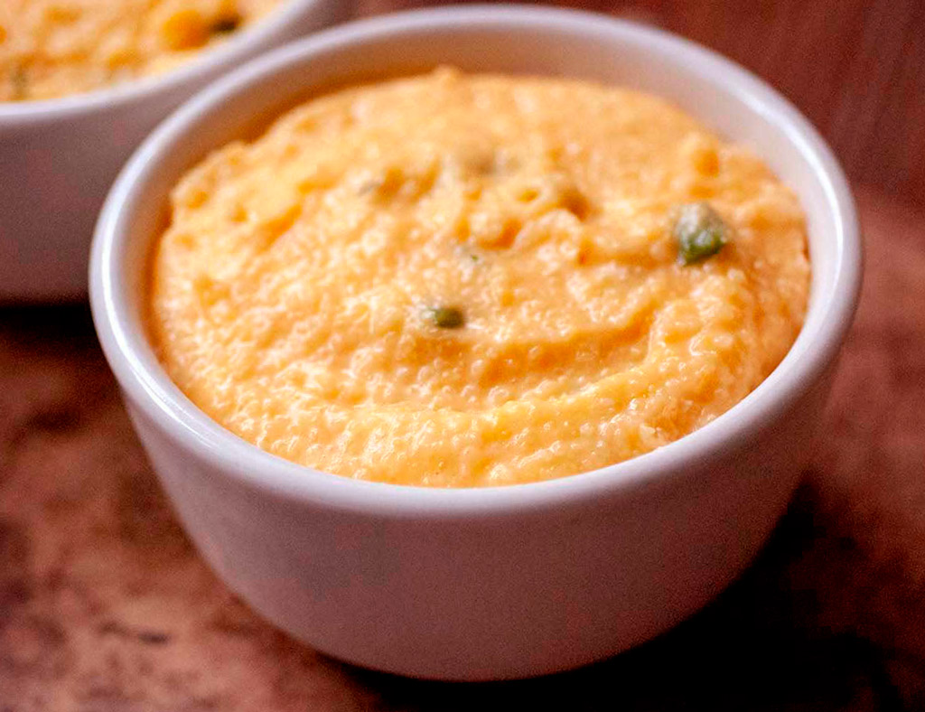 A white bowl with Maple Pumpkin Grits and pumpkin seeds on the top.