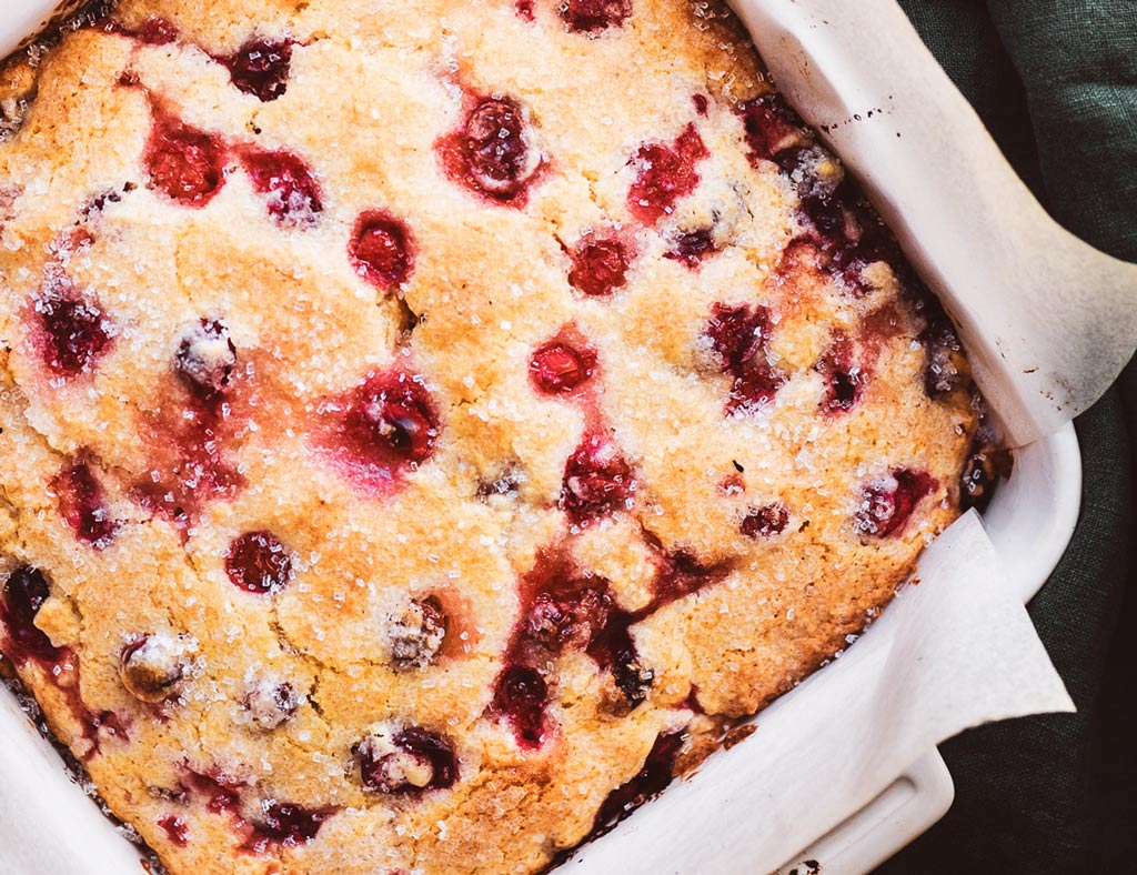 A whole, beautiful Cranberry Maple Saucy Cake in a white baking pan.