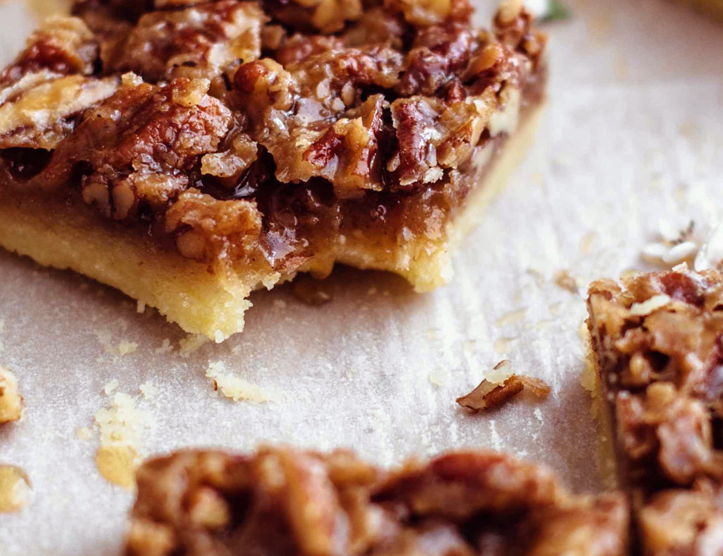 A nutty maple bar topped with pecans without a piece that was bitten off.