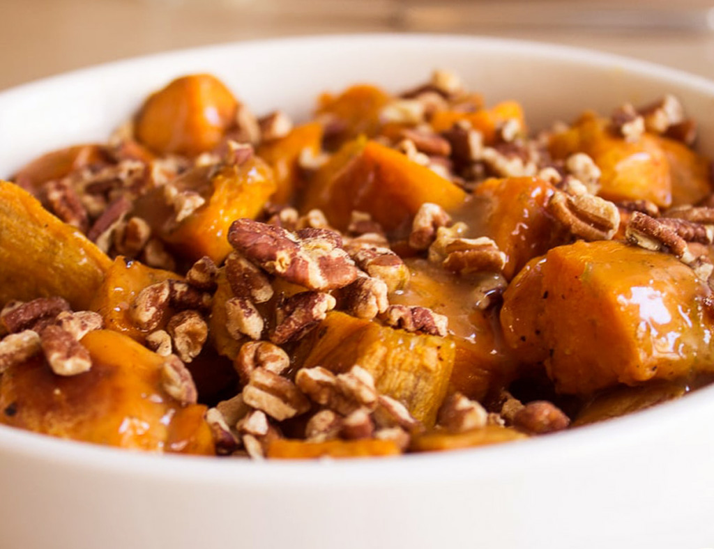 A white bowl with Maple Sweet Potatoes and Pecans.