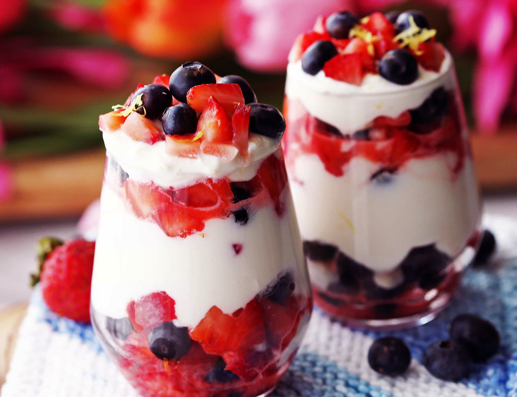 Two tall serving glasses with Fresh Berries and Maple Cream.